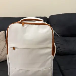 Mochila branco e marrom apoiada no sofá